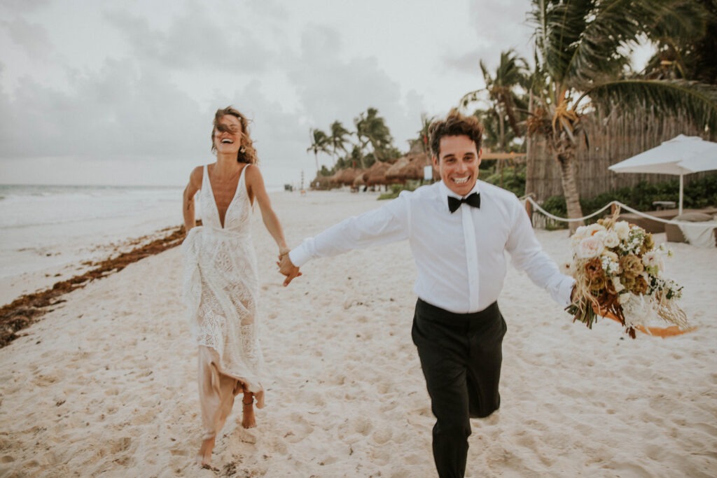 A couple running on the beach on their wedding day
